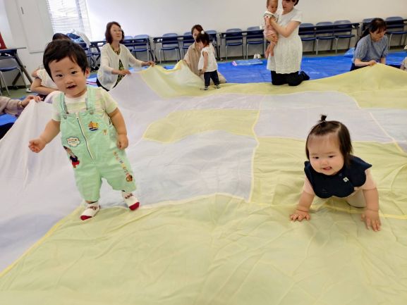 大きな布で遊んでいる親子
