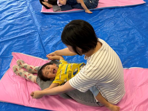 音楽に合わせてふれあいあそびを楽しんでいる親子