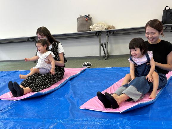 子どもを膝の上に乗せて遊んでいる親子