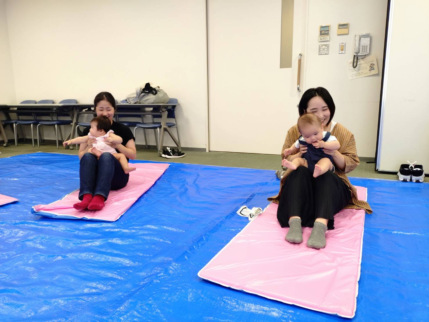 子どもを膝に乗せてふれあいあそびを楽しんでいる親子